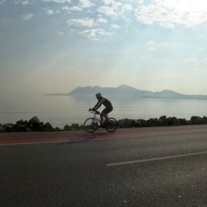 Cyclist riding his bike in Majorca along the shoreline of the magnificent Port de Pollença bay while on a organised cycling holiday in Majorca with tour operator "European Cycling Tours"