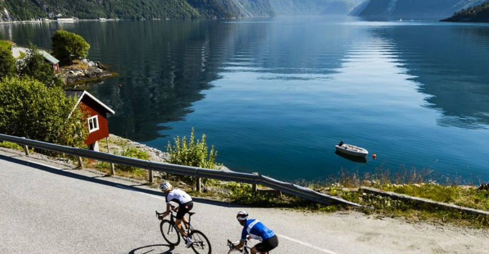 cyclists in Norway cycling along a beautiful fjord while on the Norway Atlantic coast ride high up in the Arctic circle - now booking for the 2026 season