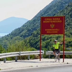 Cyclist at the Montenegro border sign enjoying the ride through Europe from Dubrovnik to Thessaloniki with cycling holiday organiser European Cycling Tours