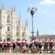 Group of cyclists celebrating the finish of a munich to milan tour at milan cathedral