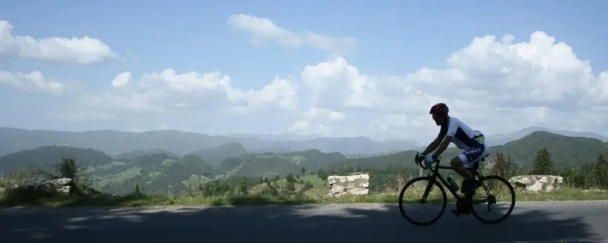 A panoramic view of a cyclist on a scenic winding road with a transylvanian mountain backdrop explore our detailed guide to planning a professional cycling holiday in romania