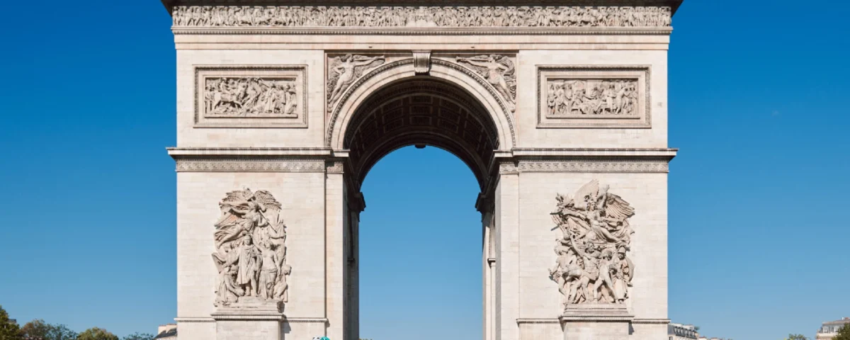 A group of cyclists riding past the arc de triomphe in paris during a guided london to paris tour view our detailed guide on choosing the best route for your cross channel adventure