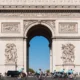 A group of cyclists riding past the arc de triomphe in paris during a guided london to paris tour view our detailed guide on choosing the best route for your cross channel adventure
