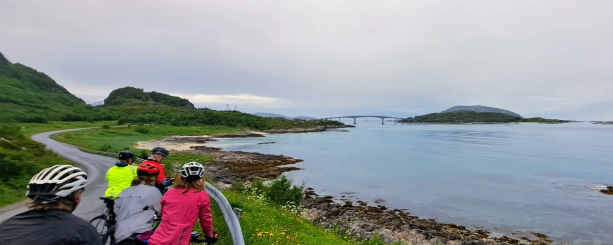 A group of cyclists admiring the panoramic coastal view and the sommarøy bridge during a guided arctic cycling tour in norway view our full atlantic coast itinerary for more details