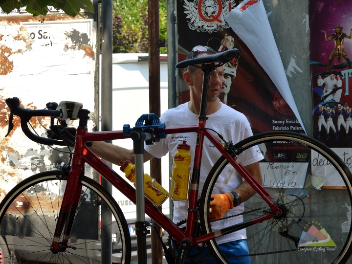 Close-up of a support team member maintaining a road bike during a cycling trip in Europe; learn more about the benefits of our guided service.