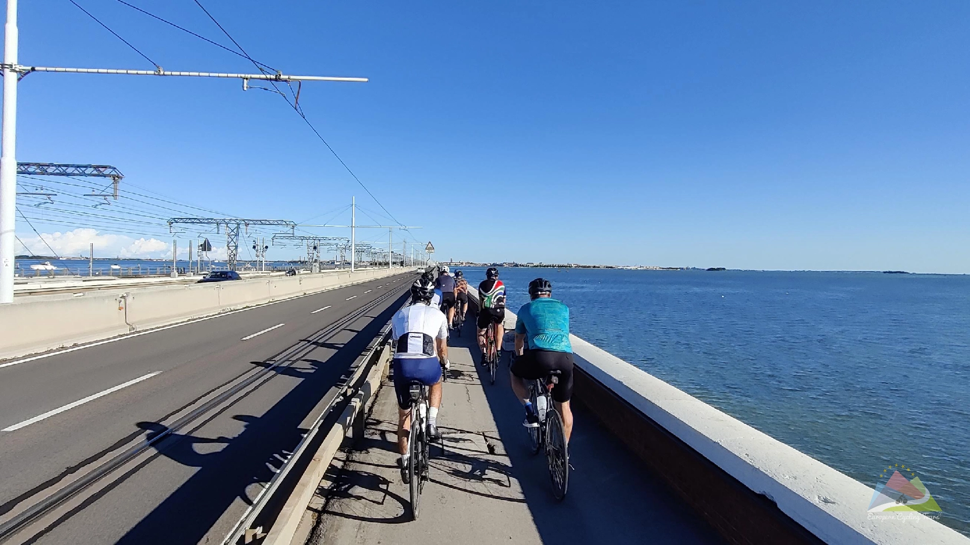 Cyclists on the spectacular venice causeway cyclepath in the veneto region during an organized road cycling tour completion explore our trans alpine cycling vacations