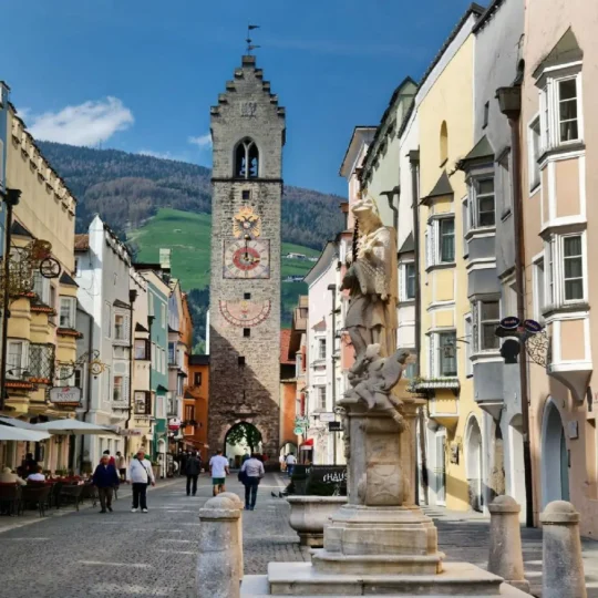 Cyclists exploring the beautiful vipitino alpine town centre in south tyrol during an organised road cycling tour enjoying delightful cultural immersion discover our trans alpine itineraries