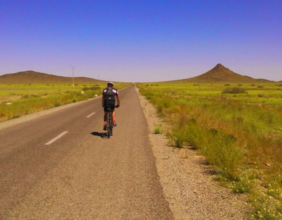The erg chebbi approach in the drâa tafilalet region featuring vast desert plains for guided road cycling providing adventurous serenity for a cyclist riding toward the dunes explore our morocco itineraries